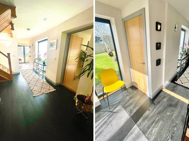 A hallway with dark wood flooring a stairway a runner rug a glass console table with plants a wooden door and a yellow chair next to a large window at Avalennek in St Newlyn East