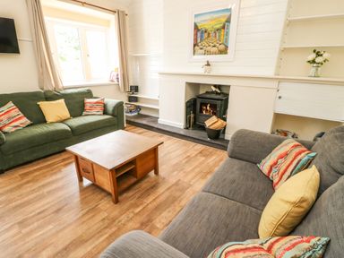 A living room with sofas a coffee table and a fireplace at Y Bwthyn Bach in Tregarth