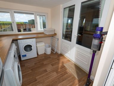 A utility room with washing machines a vacuum cleaner and laundry baskets at The Lodge in Rhosybol