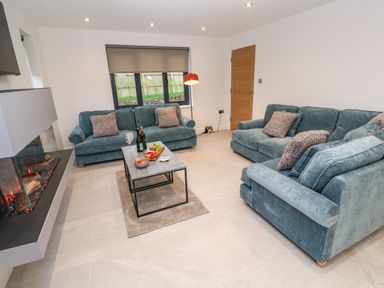 A living room with two blue sofas a coffee table a fireplace and a window at Tredarn in Connor Downs