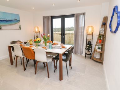 A dining room with a table set for breakfast and double glass doors at Tredarn in Connor Downs