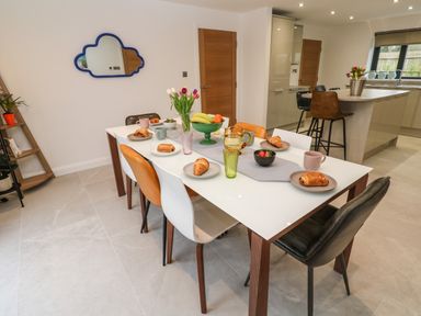 A dining area with a table set for breakfast and kitchen in the background at Tredarn in Connor Downs