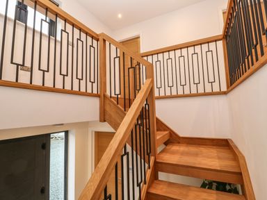 A wooden staircase with black metal railings inside a house at Tredarn in Connor Downs