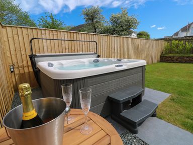 A garden with a hot tub table with champagne and glasses and wooden fencing at Tredarn in Connor Downs