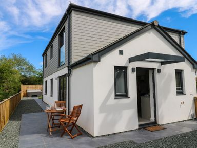 A modern two-story house with a small patio table and chairs outside at Tredarn in Connor Downs