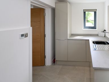 A kitchen with grey cabinets a sink a window and an open wooden door at Tredarn in Connor Downs