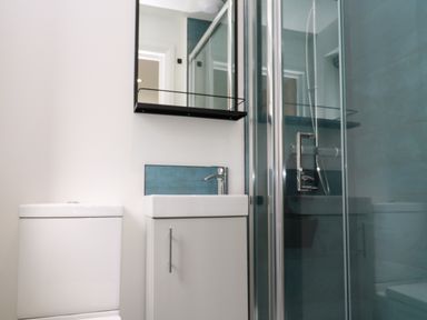 A bathroom with a toilet a sink with cabinet a mirror and a glass shower enclosure at Tredarn in Connor Downs