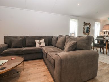 A living room with a large gray sectional sofa and a round coffee table at Ruperts Retreat in Nateby near Garstang