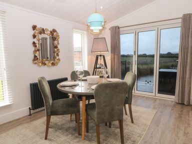 A dining area with a round table set for four near glass doors overlooking fields at Ruperts Retreat in Nateby near Garstang