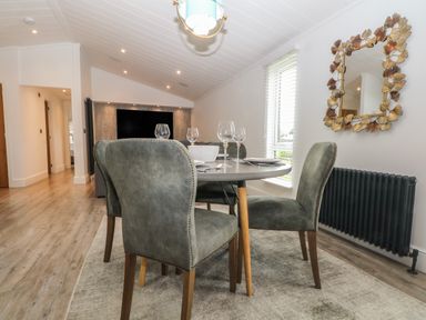 A dining table with four chairs and glassware in a room with a window and a decorative wall mirror at Ruperts Retreat in Nateby near Garstang