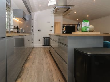 A modern kitchen with gray cabinets, a wooden countertop island, and kitchen appliances at Ruperts Retreat in Nateby near Garstang