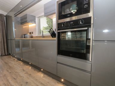 A modern kitchen with gray cabinets an oven a microwave a toaster and knives on a countertop at Ruperts Retreat in Nateby near Garstang