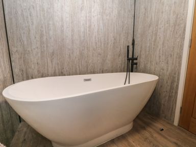 A freestanding bathtub with black faucet fixtures in a bathroom at Ruperts Retreat in Nateby near Garstang