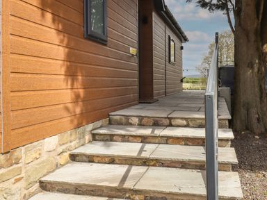 Stone steps with metal handrail leading to a wooden building with horizontal cladding at Ruperts Retreat in Nateby near Garstang