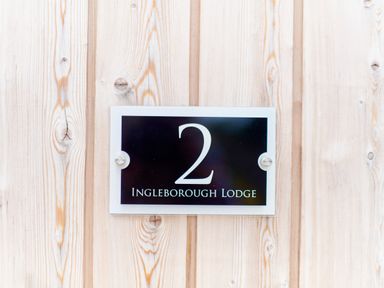 A black house number plaque with number 2 and Ingleborough Lodge text on wooden wall at Ingleborough Lodge in Rathmell near Settle