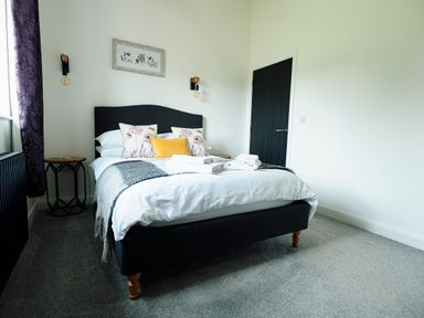 A bedroom with a bed and folded towels on top at Ingleborough Lodge in Rathmell near Settle