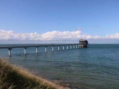 A long pier extending over the sea leading to a round building at Crosswinds 68 in Bembridge