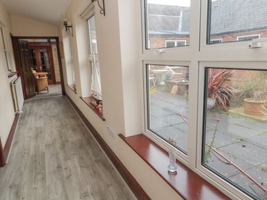 A hallway with large windows along one side and a door leading to another room at Barnacre in Longhirst near Morpeth