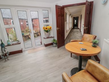A room with two brown chairs and a round wooden table near glass doors opening to a courtyard at Barnacre in Longhirst near Morpeth