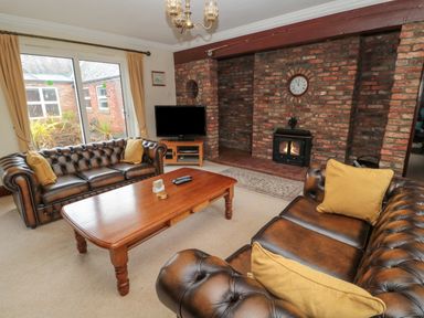 A living room with leather sofas a wooden coffee table a tv and a brick fireplace at Barnacre in Longhirst near Morpeth