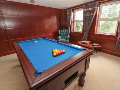 A room with a pool table a green armchair and a small table with board games at Barnacre in Longhirst near Morpeth