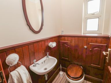 A small bathroom with a sink toilet mirror towel rack and window at Barnacre in Longhirst near Morpeth