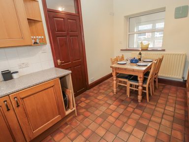 A kitchen with wooden cabinets a wooden dining table set for four and a window at Barnacre Longhirst near Morpeth