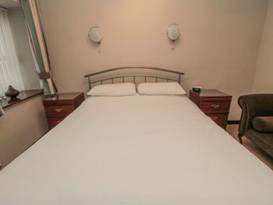 A bedroom with a metal frame bed two pillows bedside tables with drawers wall lights and a window with curtains at Barnacre Longhirst near Morpeth