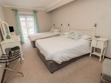 A bedroom with two beds bedside tables a dressing table and a luggage rack at Barnacre in Longhirst near Morpeth