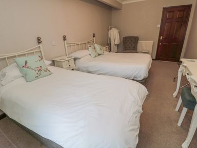 A bedroom with two beds bedside tables an armchair a desk and a door at Barnacre in Longhirst near Morpeth