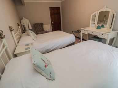A bedroom with two beds a dressing table and an armchair at Barnacre in Longhirst near Morpeth