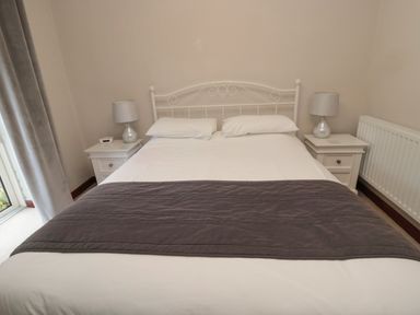 A bedroom with a double bed two bedside tables with lamps and a radiator at Barnacre in Longhirst near Morpeth