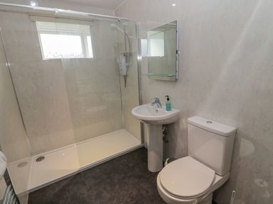 A bathroom with a toilet sink mirror and a glass enclosed shower at Barnacre in Longhirst near Morpeth