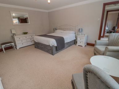 A bedroom with a double bed two bedside tables and two armchairs at Barnacre Longhirst near Morpeth
