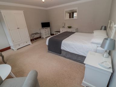 A bedroom with a double bed a television on a dresser and an armchair at Barnacre Longhirst near Morpeth