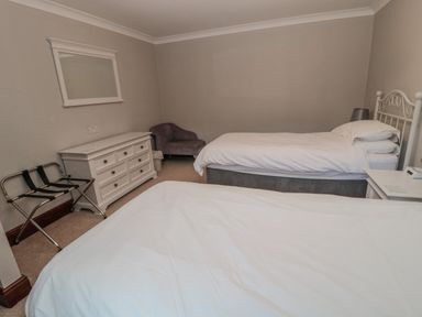 A bedroom with two single beds a dresser a chair and a luggage rack at Barnacre in Longhirst near Morpeth