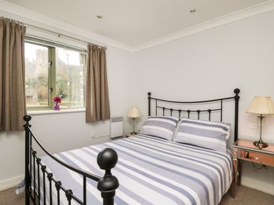 A bedroom with a double bed with striped bedding a window with curtains and bedside tables with lamps at Flat 2 in Pembroke