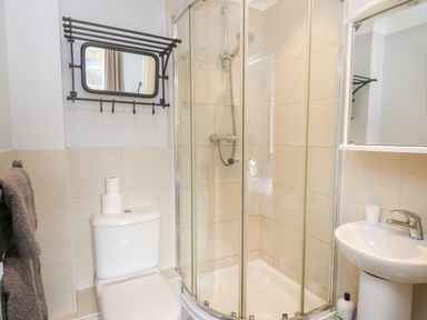 A bathroom with a shower enclosure toilet sink mirror and towel rack at Flat 2 in Pembroke