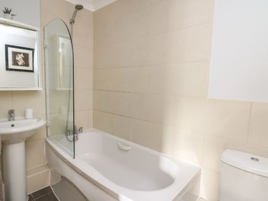 A bathroom with a bathtub shower combination sink with mirror and toilet at Flat 2 Pembroke
