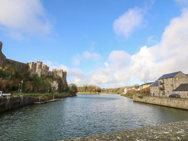 A river with a castle on the left and stone buildings on the right at Flat 2 in Pembroke