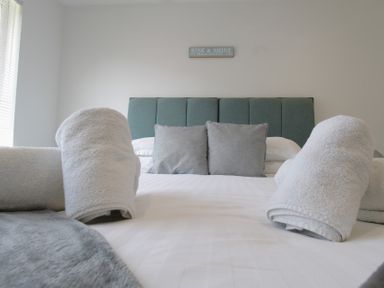 A bedroom with bed and towels rolled on it at 65 Channel View in Ilfracombe