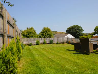 A garden with grass and seating area at 65 Channel View Ilfracombe