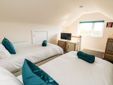 A bedroom with two beds a television on a cabinet and a window at The Chocolate Box in Weymouth