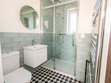 A bathroom with a toilet sink shower and patterned floor tiles at The Chocolate Box in Weymouth