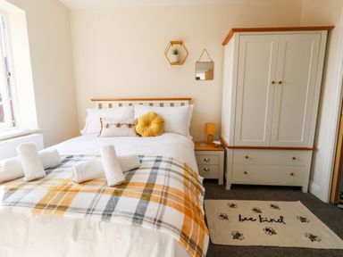 A bedroom with a bed with rolled towels a nightstand wardrobe and a rug with bees at The Chocolate Box in Weymouth
