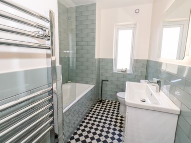 A bathroom with a bathtub toilet sink and heated towel rail at The Chocolate Box in Weymouth
