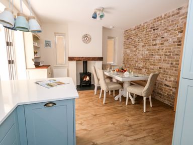A dining area with a table set for breakfast next to a brick wall and a fireplace in a kitchen at The Chocolate Box in Weymouth