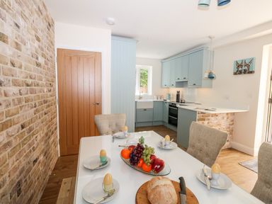 A kitchen and dining area with a table set with eggs bread and fruit and blue cabinets at The Chocolate Box in Weymouth