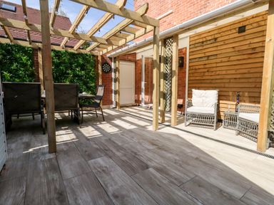 An outdoor patio with wooden pergola seating area and dining table at The Chocolate Box in Weymouth