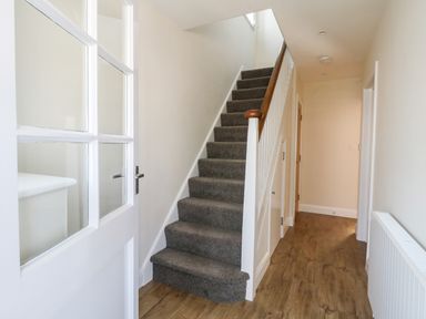 A hallway with carpeted stairs and wooden flooring at The Chocolate Box in Weymouth